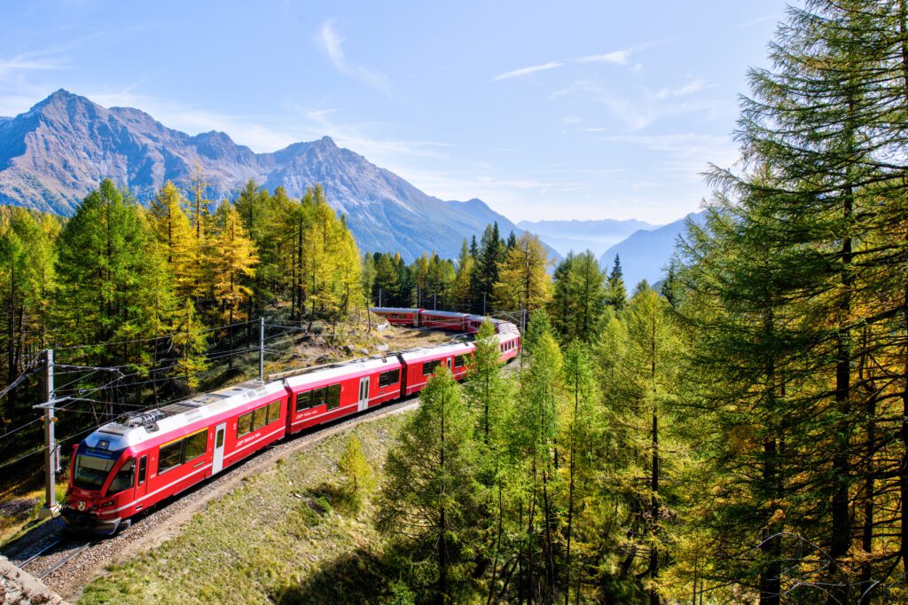 The vibrant red Bernina Express train curving through the Swiss Alps, an unmissable part of a European Interrail itinerary or a breathtaking alpine train adventure.