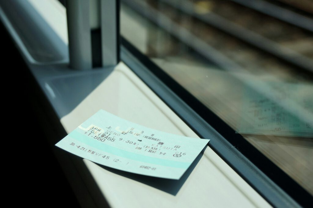 An Interrail or Eurail train pass resting on a train window sill, with the tracks visible in the background, symbolizing train travel across Europe.
